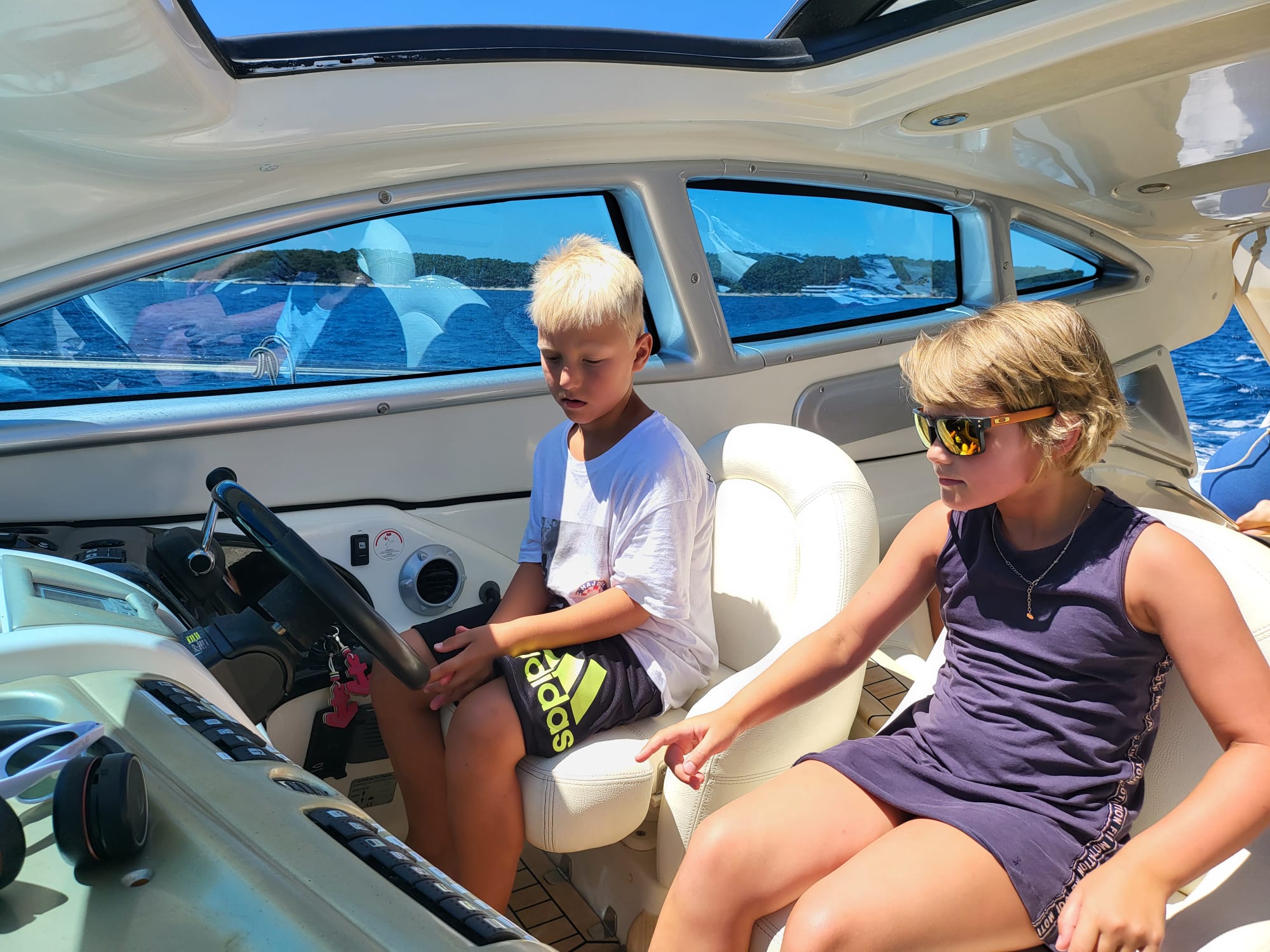 Zwei Kinder steuern ein Motorboot